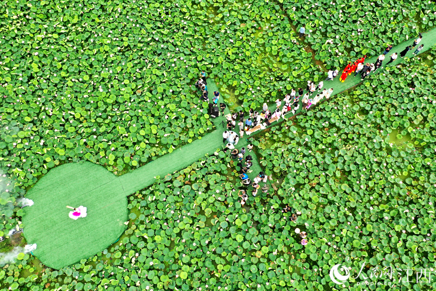演員正在蓮池的舞臺上演出，吸引著游客們圍觀。 人民網 時雨攝