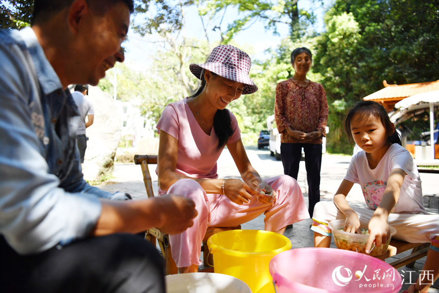 蓮池旁的竹蔭下，村民們圍聚在一起邊嘮家常邊手工加工白蓮。 人民網 時雨攝