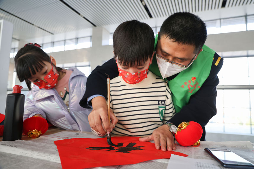南鐵永安車務段青年志愿者帶領兒童旅客寫“?！?。張海根攝