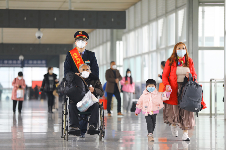 三明北站迎春花志愿者服務臺工作人員幫助旅客乘車。 張海根攝