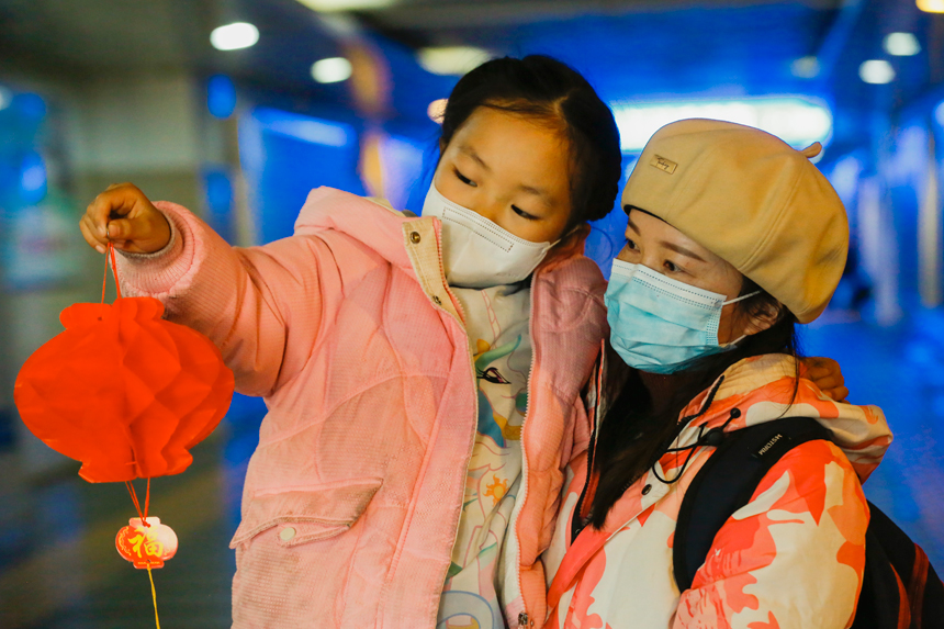 “小候鳥”侯令儀拿著彩燈籠與家人在候車室合影留念。于永生攝