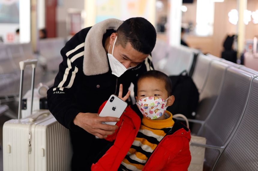 2023年1月6日，江西鷹潭北站候車室內，一對父子正在與家人進行視頻通話，向家人報平安。蔡紫妍攝