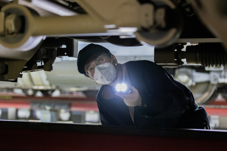南昌西車輛段的動車機組械師正在俯下身子對歸來的列車進行檢修。李桐攝