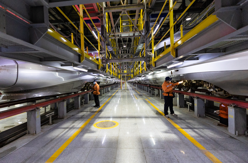 南昌西車輛段的兩動車機械師一左一右在對歸來的列車進行檢修。李桐攝