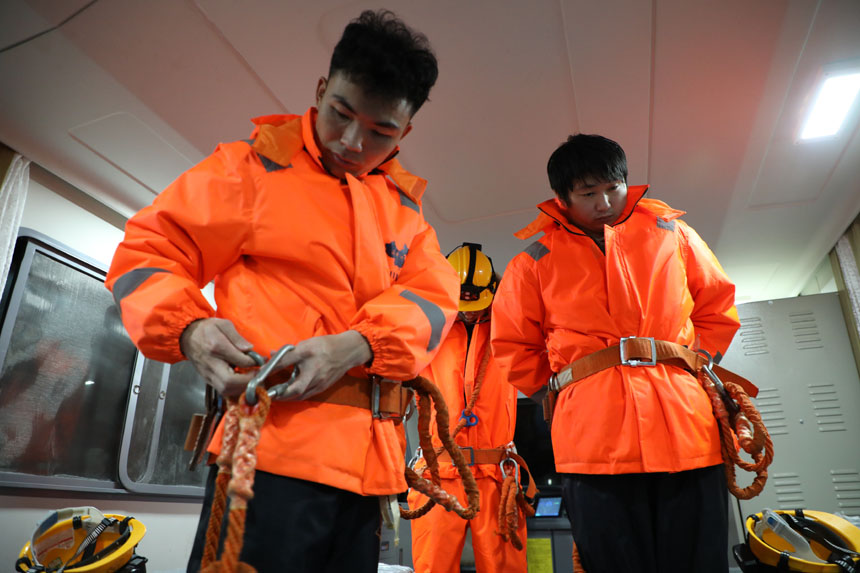 作業前胡朋和工友們系上安全帶，做好安全措施。李金明攝