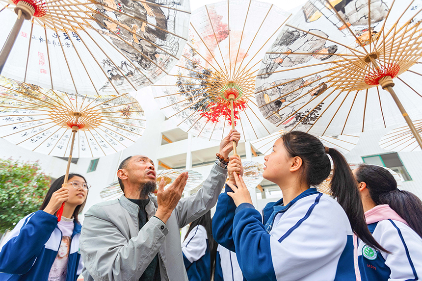 當地油紙傘制作技能大師在向孩子們講解油紙傘的制作技藝。王惠民攝