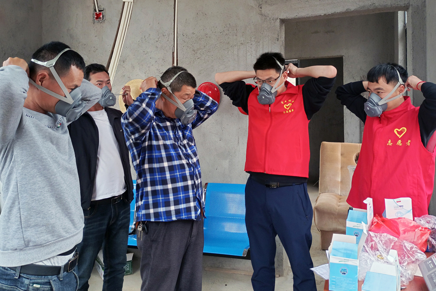 宜豐縣綜投集團公司志愿者為項目工地建筑工人演示防塵口罩使用方法。陳兵攝 