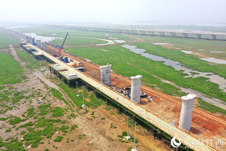 湖中已建成的高鐵橋墩與不遠處的快速路遙相呼應。 人民網 時雨攝