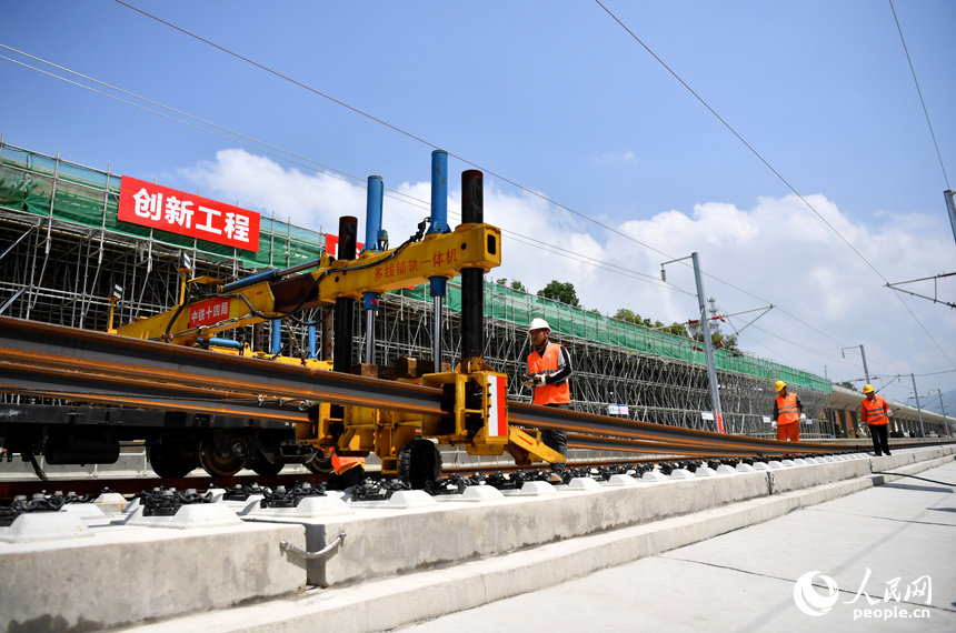 浮梁東站內多線鋪軌一體機正在將鋼軌鋪入無砟軌道承軌槽中。 人民網記者 時雨攝