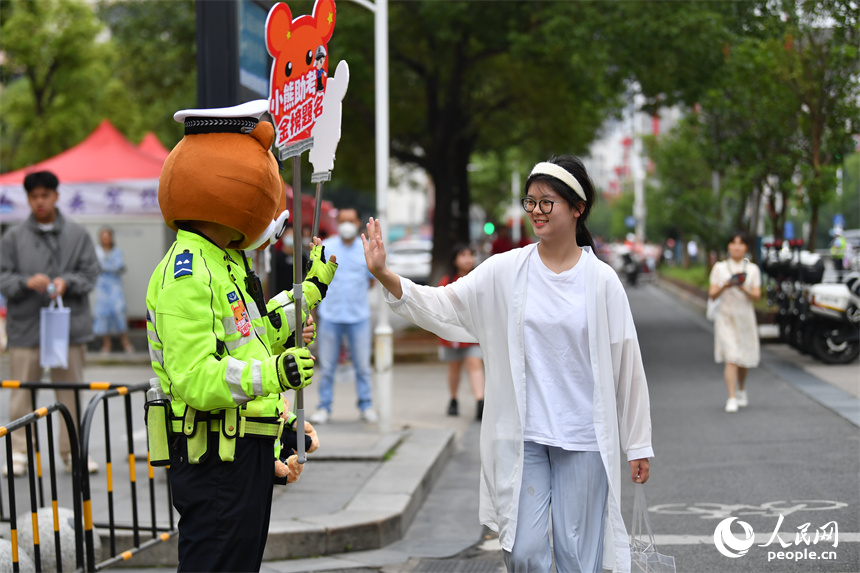圖為“小熊交警”和考生擊掌鼓勵。 人民網記者 時雨攝