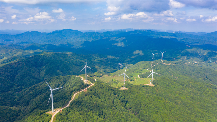 一臺臺風力發電機矗立在群山之巔，美不勝收。李凡欽攝