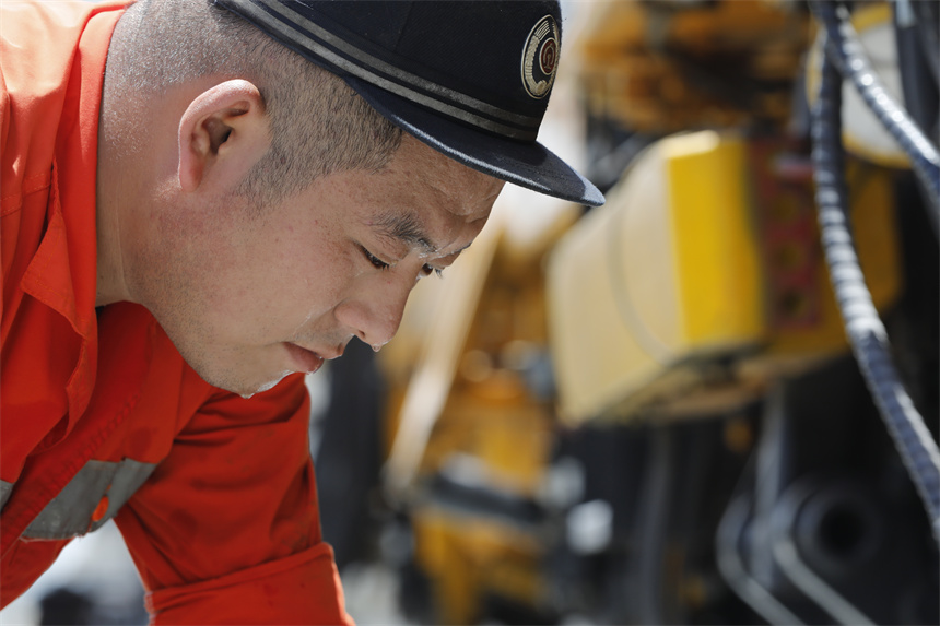 工人正在頂著高溫對車輛進行養護作業，豆大的汗珠從鼻尖劃落。汪翰攝