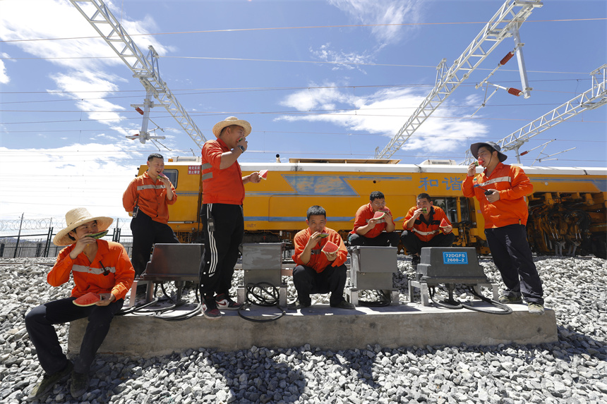 工人們在高溫精調施工作業間隙吃西瓜消暑。汪翰攝