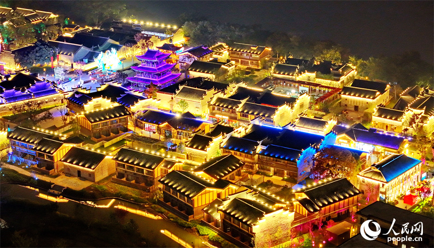 夜色中的七鯉古鎮，與遠處城市高樓大廈相輝映，古色古韻與現代氣息的交融，吸引了許多游客。人民網 朱海鵬攝