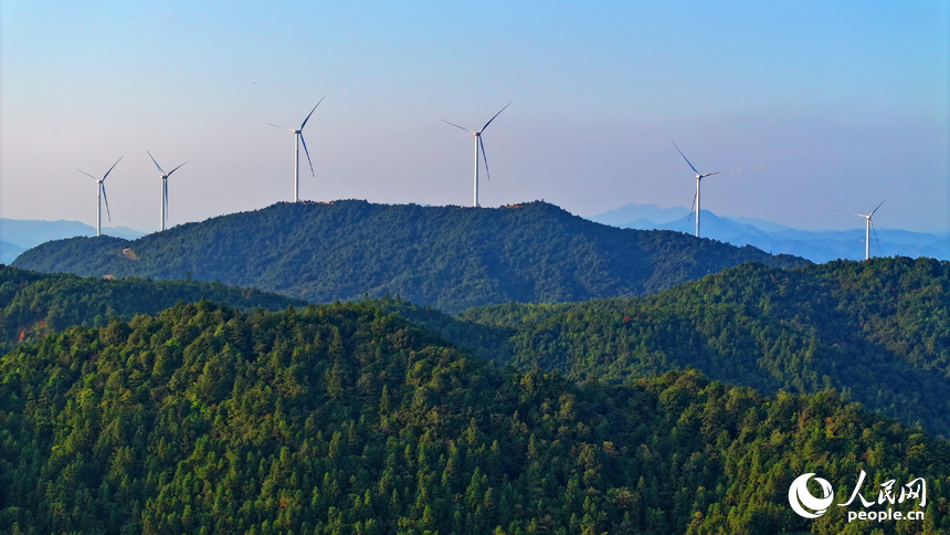 贛州市定南縣歷市鎮群山之上，風力發電機迎風旋轉，轉化為清潔電源并入電網輸往工廠企業、千家萬戶。人民網 朱海鵬攝