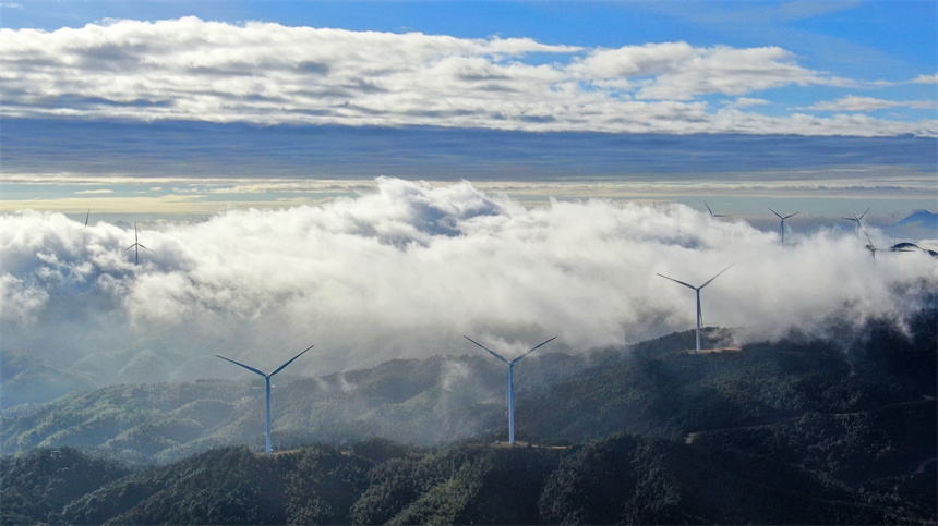 一臺臺風力發電機矗立在群山之巔，蔚為壯觀。詹繼成攝