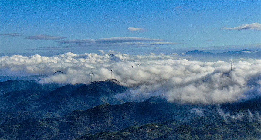 一臺臺風力發電機矗立在群山之巔，蔚為壯觀。詹繼成攝