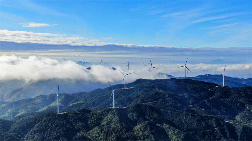 一臺臺風力發電機矗立在群山之巔，蔚為壯觀。詹繼成攝