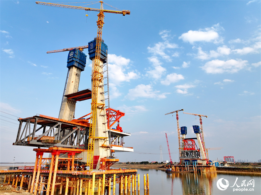 南昌市東湖區揚子洲鎮贛江河畔塔吊矗立，設備有序運轉，工人在隆興大橋項目工地忙碌。人民網 朱海鵬攝