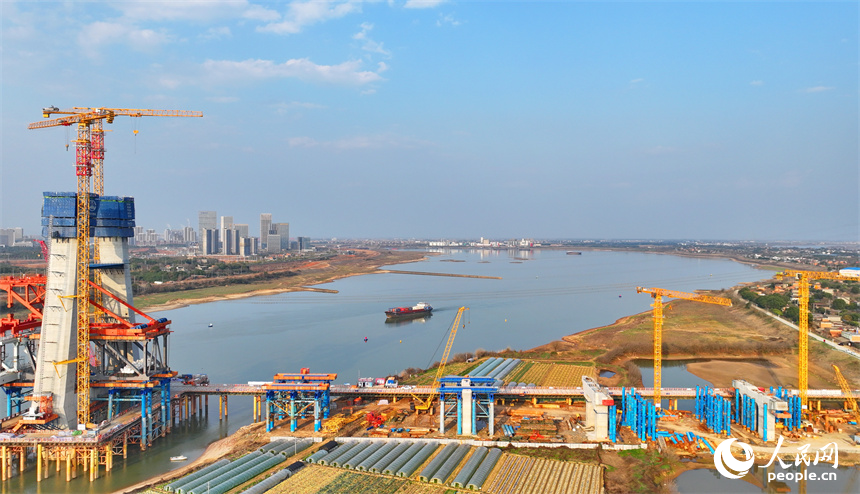 南昌市東湖區揚子洲鎮贛江河畔塔吊矗立，設備有序運轉，工人在隆興大橋項目工地忙碌。人民網 朱海鵬攝