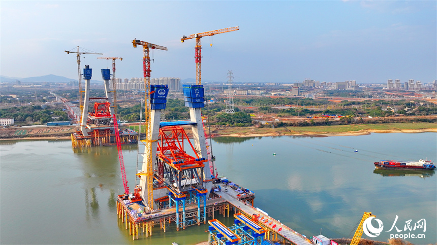 南昌市東湖區揚子洲鎮贛江河畔塔吊矗立，設備有序運轉，工人在隆興大橋項目工地忙碌。人民網 朱海鵬攝