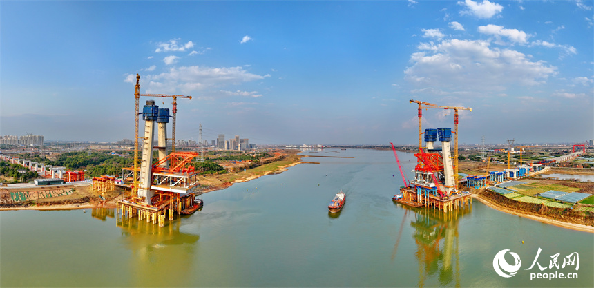 南昌市東湖區揚子洲鎮贛江河畔塔吊矗立，設備有序運轉，工人在隆興大橋項目工地忙碌。人民網 朱海鵬攝