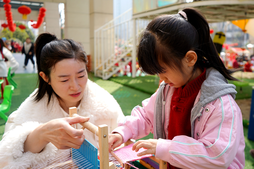 孩子在家長的指導下學習紡織。陳旗海攝
