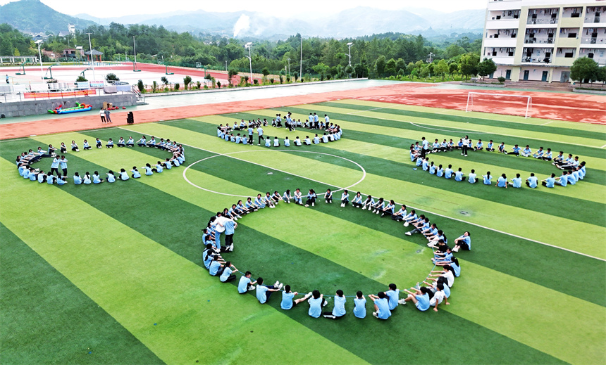 學生之間相互攙扶，在動力繩上行走。呂春華攝