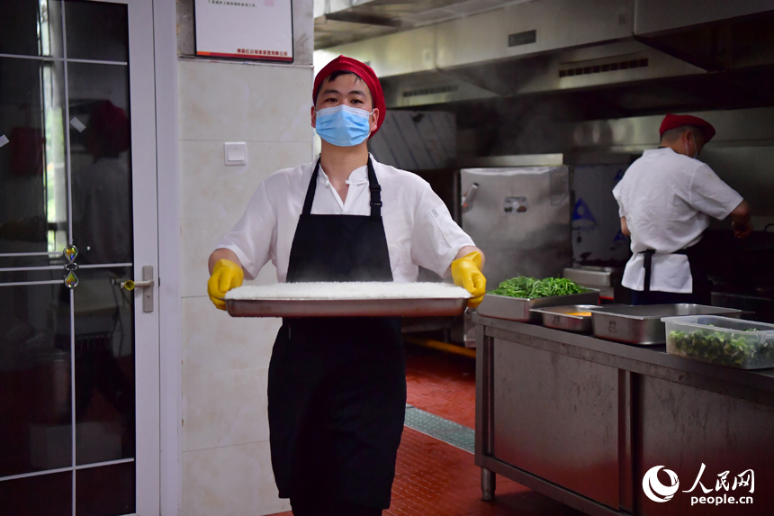 紅谷灘區九龍馨苑社區的幸福食堂后廚，工作人員將蒸好的米飯端往打菜窗口。人民網記者 時雨攝