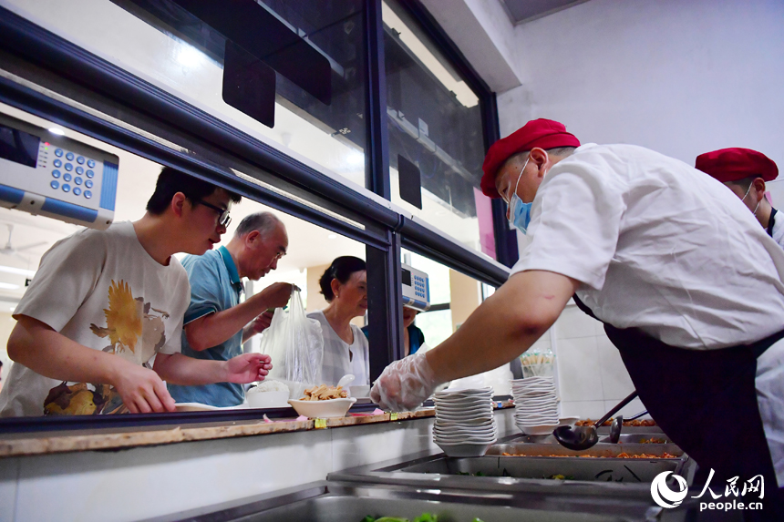 紅谷灘區九龍馨苑社區的幸福食堂里，居民們正在打菜。人民網記者 時雨攝