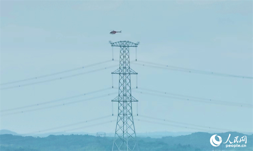 直升機穿梭在特高壓電線旁開展特高壓工程驗收作業。人民網記者 時雨攝