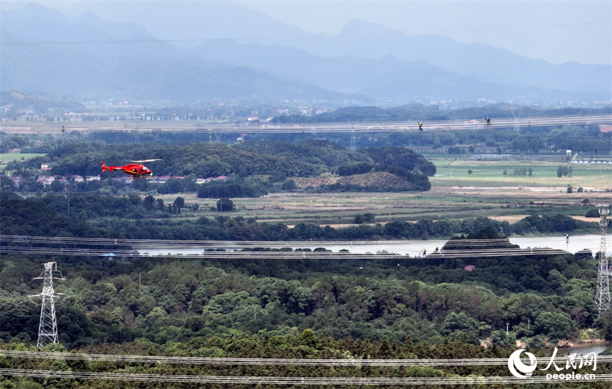 直升機穿梭在特高壓電線旁開展特高壓工程驗收作業。人民網記者 時雨攝