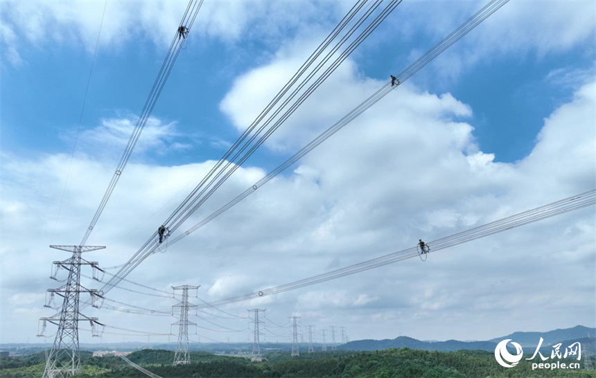 電網工作人員正在特高壓電線上走線巡檢。人民網記者 時雨攝
