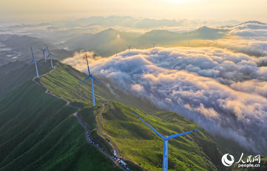 在吉安市遂川縣左溪鎮洋溪村俯瞰雙溪草山，數十臺風力發電機迎風旋轉，與朝霞、云海、青山交相輝映，風景如畫。人民網 朱海鵬攝