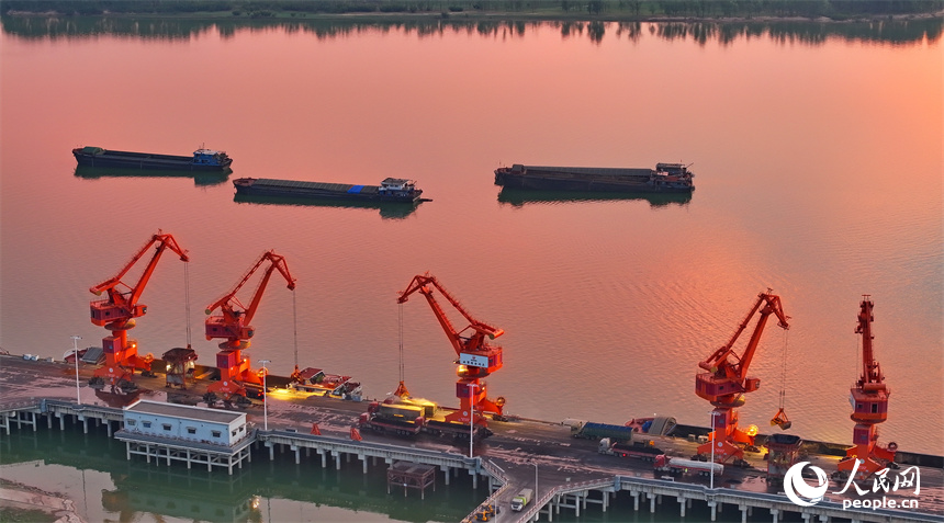 位于南昌市南昌縣的姚灣綜合碼頭，貨船、貨車來來往往，起重機裝卸作業有序進行，呈現出忙碌的景象。人民網 朱海鵬攝