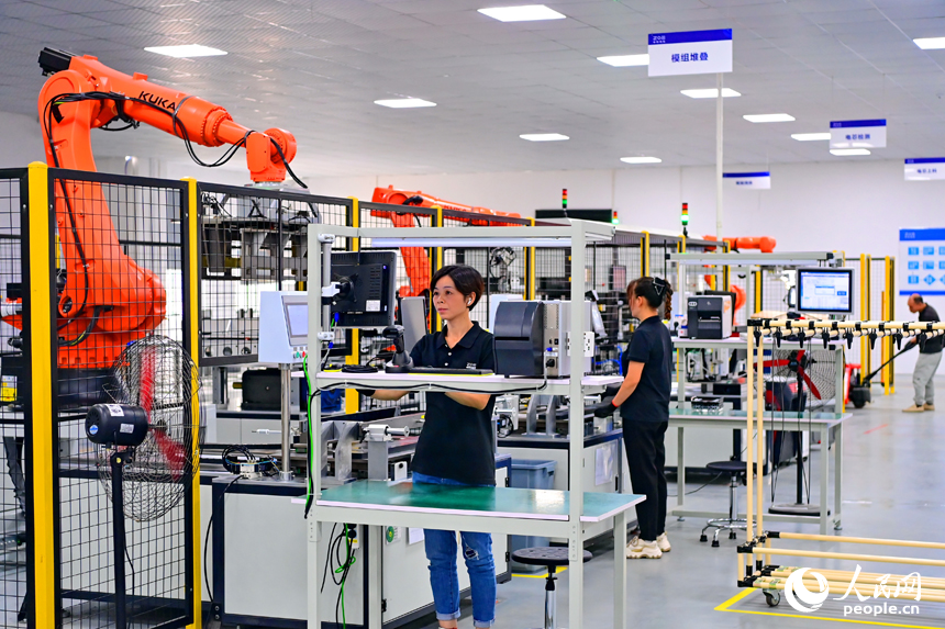 撫州市南豐縣智能制造產業園的一家儲能技術有限公司，智能機械臂來回運轉，工人在車間內忙碌。人民網 朱海鵬攝