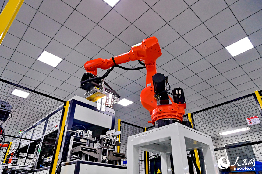 撫州市南豐縣智能制造產業園的一家儲能技術有限公司，智能機械臂來回運轉，工人在車間內忙碌。人民網 朱海鵬攝