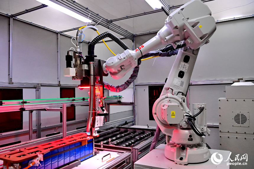 撫州市南豐縣智能制造產業園的一家儲能技術有限公司，智能機械臂來回運轉，工人在車間內忙碌。人民網 朱海鵬攝