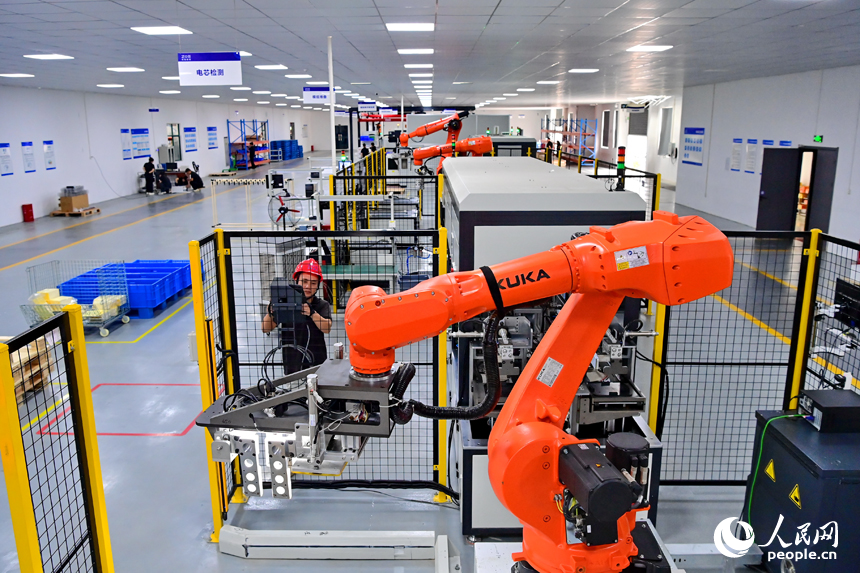撫州市南豐縣智能制造產業園的一家儲能技術有限公司，智能機械臂來回運轉，工人在車間內忙碌。人民網 朱海鵬攝