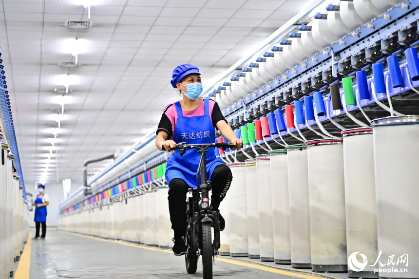 撫州市東鄉區經濟開發區的一家紡織有限公司生產車間內，工人在智能紡紗生產線上忙碌。人民網 朱海鵬攝