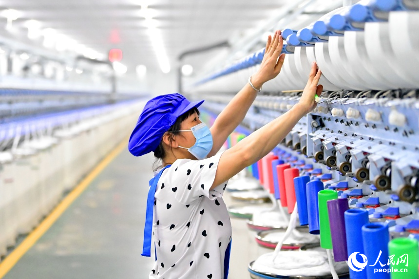撫州市東鄉區經濟開發區的一家紡織有限公司生產車間內，工人在智能紡紗生產線上忙碌。人民網 朱海鵬攝