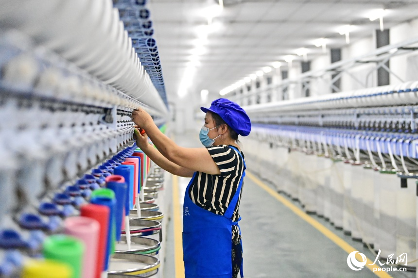 撫州市東鄉區經濟開發區的一家紡織有限公司生產車間內，工人在智能紡紗生產線上忙碌。人民網 朱海鵬攝