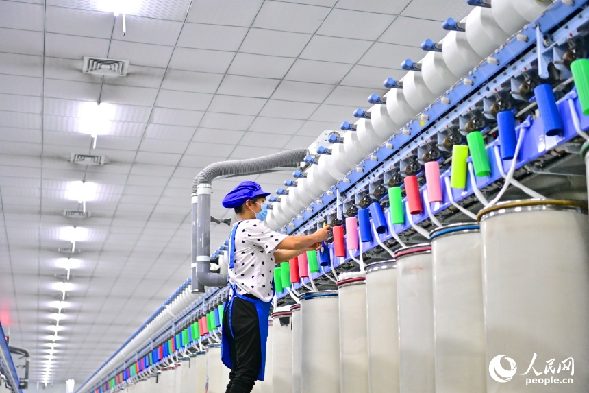 撫州市東鄉區經濟開發區的一家紡織有限公司生產車間內，工人在智能紡紗生產線上忙碌。人民網 朱海鵬攝