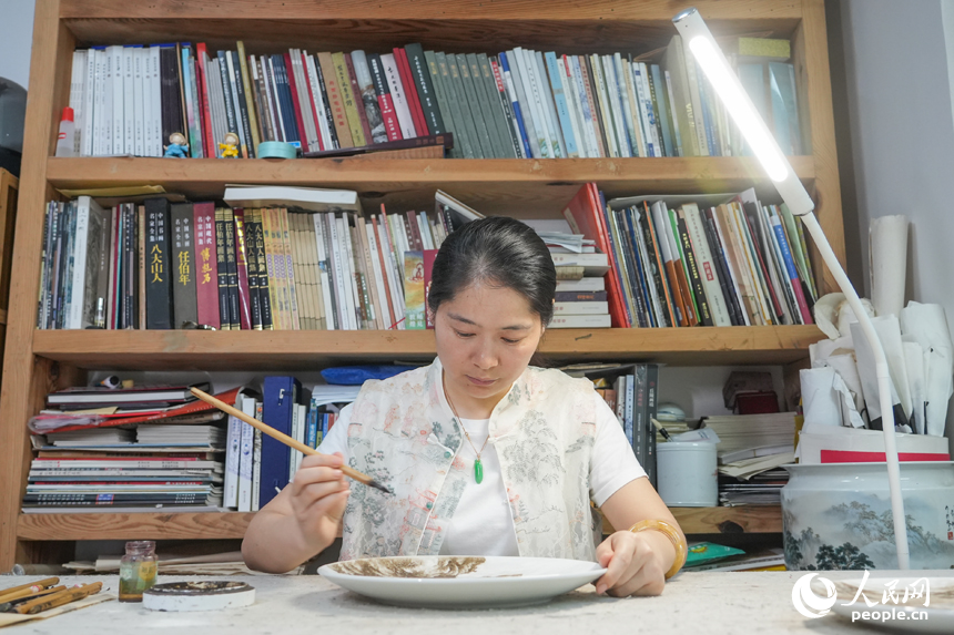 何偉珍正在進行粉彩瓷創作。人民網 孔文進攝