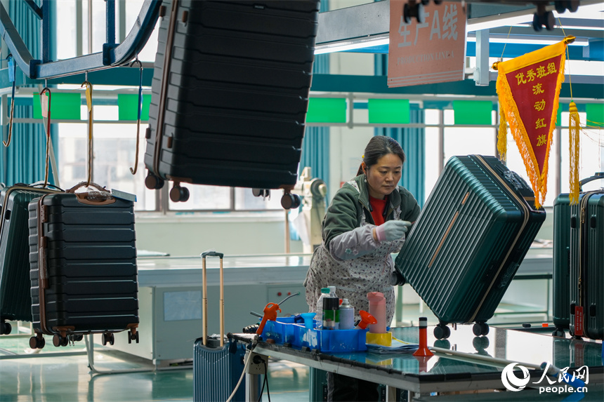 工人們正在生產線上組裝箱包。人民網 涂詩軒攝