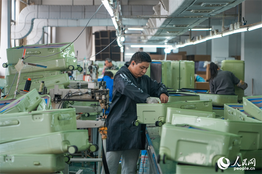 工人們正在生產線上組裝箱包。人民網 涂詩軒攝