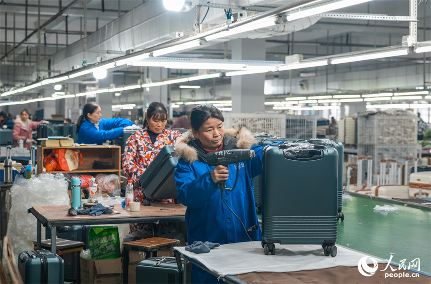 工人們正在生產線上組裝箱包。人民網 涂詩軒攝