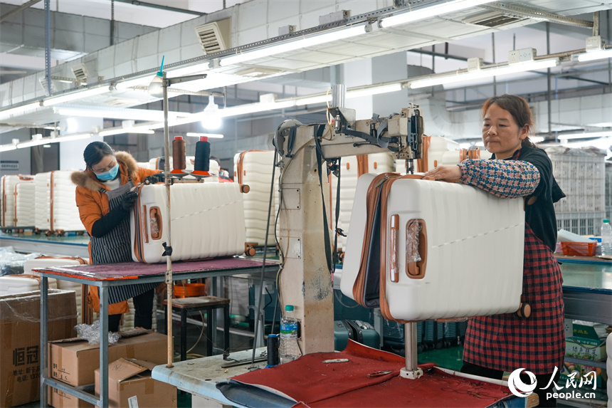 工人們正在生產線上組裝箱包。人民網 涂詩軒攝