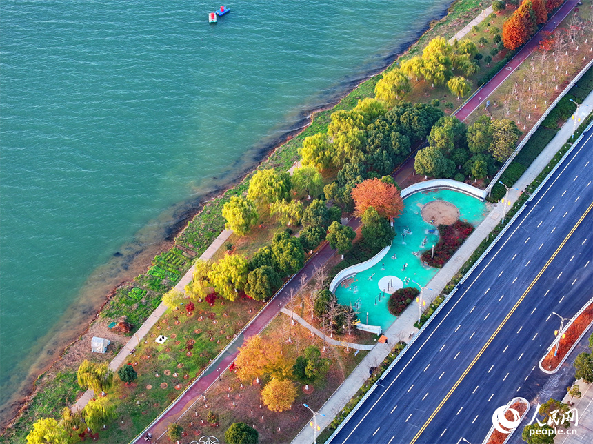 吉安市吉水縣贛江沿岸的一處“口袋公園”，許多市民在打籃球，色彩斑斕的樹木與籃球場、健身步道、碧綠江水相映襯。人民網 朱海鵬攝