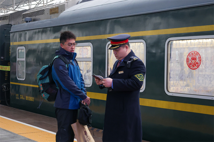 圖為K4280次旅客列車列車長陶志兵查驗旅客信息。王浩 攝